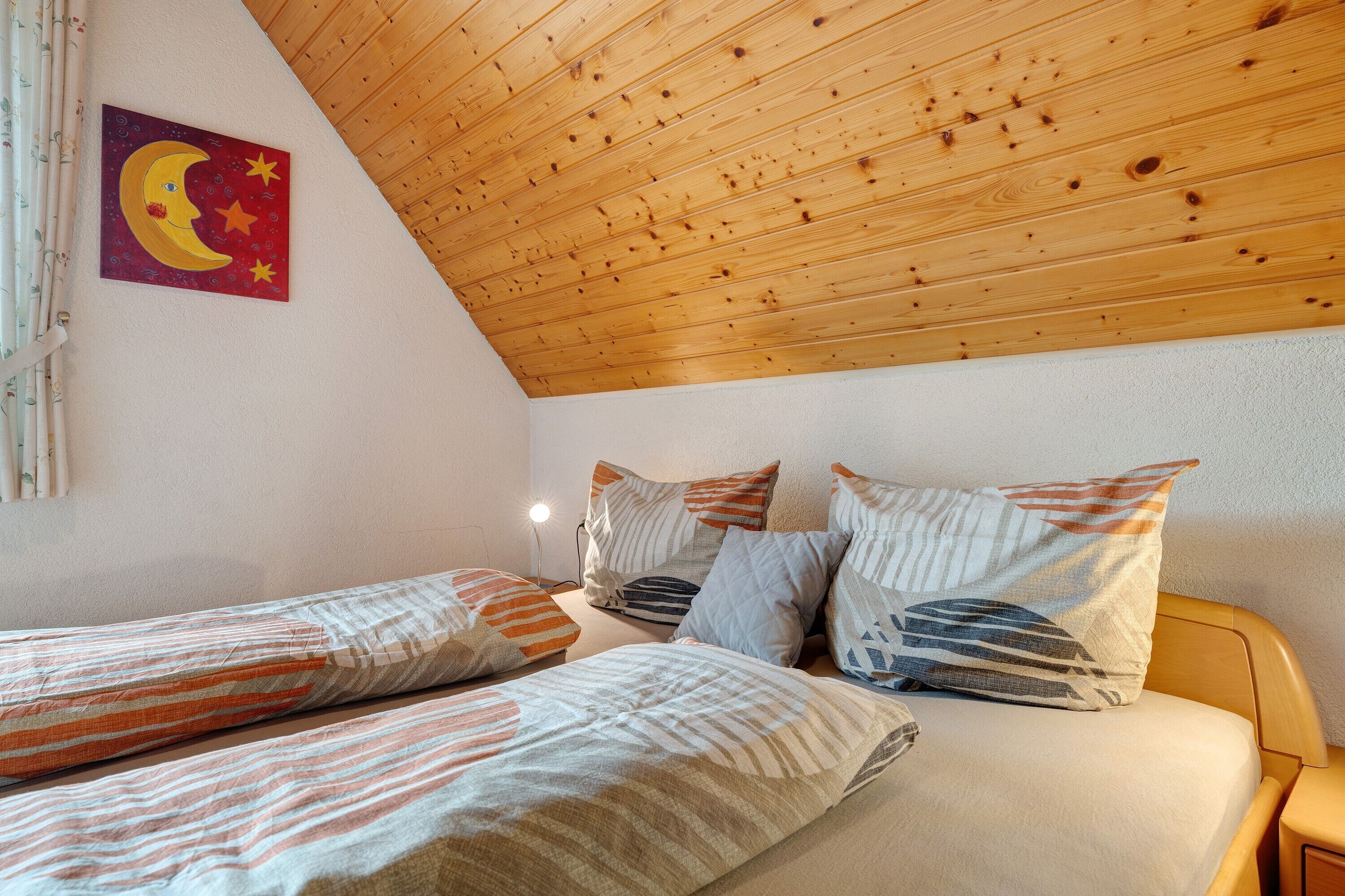 Une chambre avec deux lits simples, un plafond en bois et une œuvre d’art accrochée au mur.