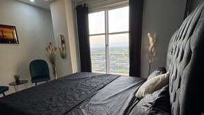 Une chambre moderne avec un grand lit, une vue sur la ville et une petite table avec une chaise.