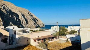 A coastal village with white buildings, a rocky cliff, and the sea in the background. - Sabbia Calda  apt 8 by Comfortbnb (Perissa)