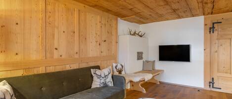 A wooden interior with a sofa, a small table, a TV, and antlers on the wall.