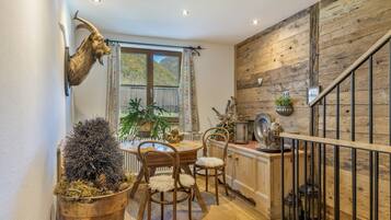 Ein rustikales Interieur mit einer Holztreppe, einem Essbereich mit Holzsesseln und einem aufgehängten Tierkopf.