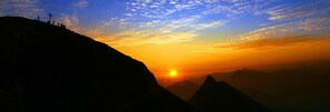 A mountain landscape with a sunset and silhouettes of people on a hill. - Apartment 'Mittagspitz' with Shared Garden and Wi-Fi (Mellau)