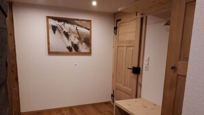 Een kamer met houten vloer, een houten deur en een lijst met een afbeelding aan de muur.