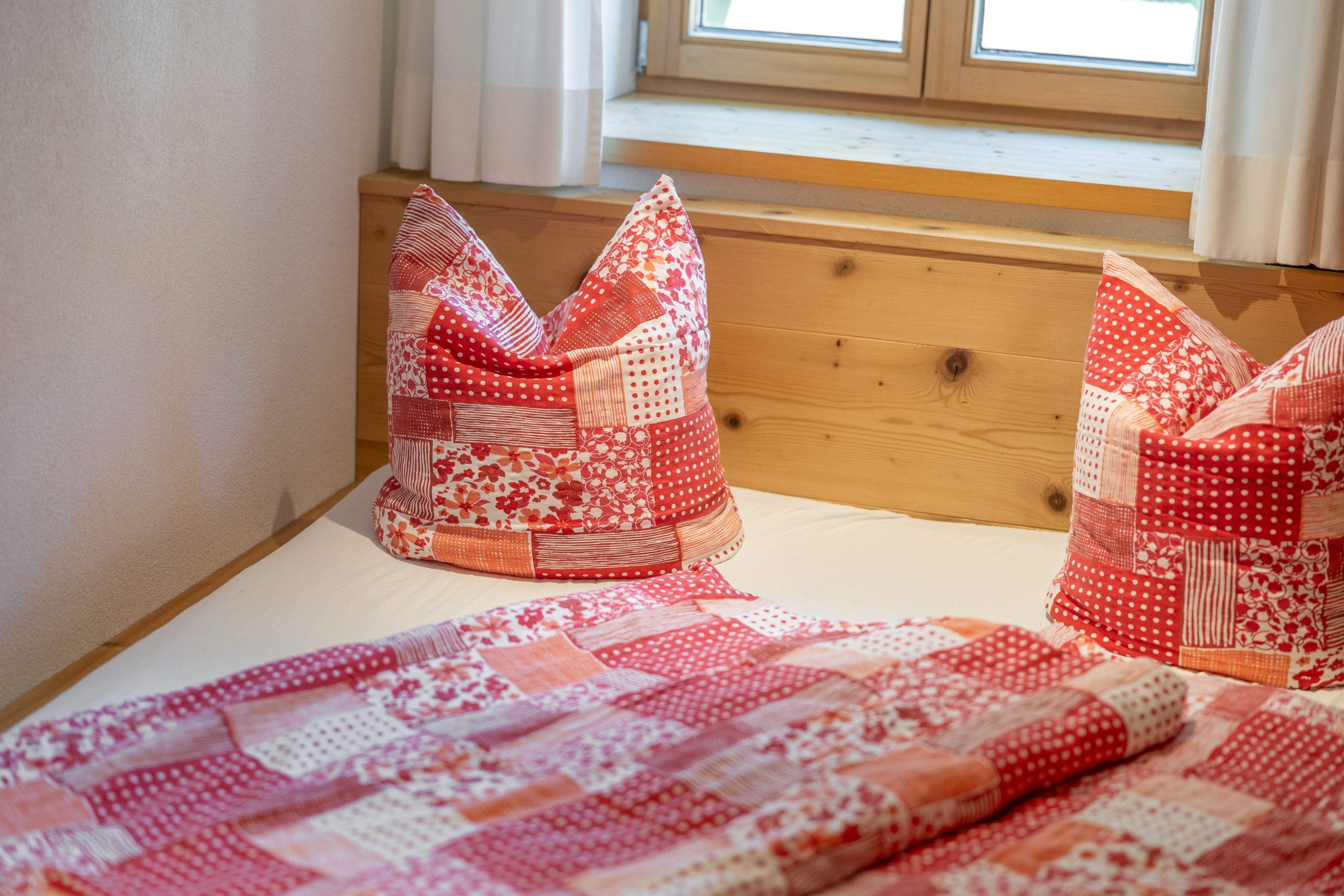 Una cama con colcha y dos almohadas de estampado floral.