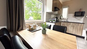 Une cuisine moderne avec une table à manger en bois, des chaises noires et une fenêtre avec des rideaux.