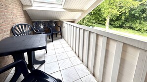 Une terrasse couverte avec une table et des chaises, un mur en briques et une vue sur la verdure.