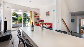 A spacious dining area with a long table, chairs, a bookshelf, and a red sofa. - Lake Constance Holiday Home Brunnenberg – Relaxation Close to the Lake (Sipplingen)