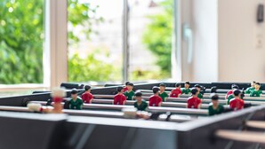 Uma mesa de futebol de mesa com jogadores de uniforme vermelho e verde.