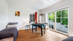 Quarto com cama, mesa de pebolim, janela com vista e porta.
