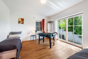 Une chambre avec un lit, une table de baby-foot, une fenêtre donnant sur un beau paysage et une porte.