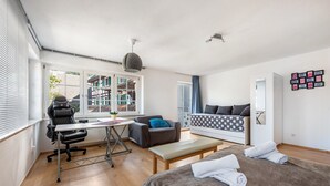 A modern room with a bed, a desk, a chair, a sofa, and a window with blinds. - Lake Constance Holiday Home Brunnenberg – Relaxation Close to the Lake (Sipplingen)