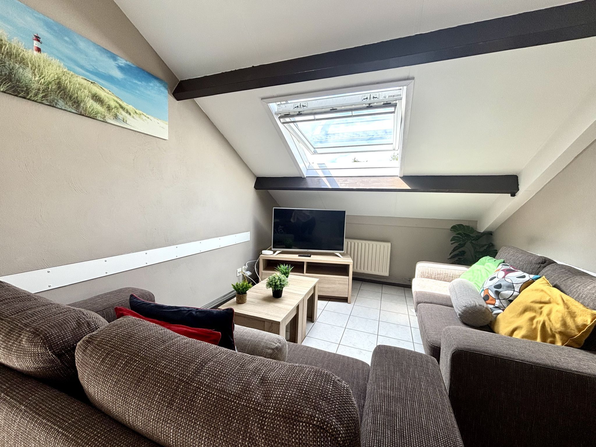 Una sala de estar acogedora estilo loft, con un ventanal grande, un televisor de pantalla plana y asientos cómodos.