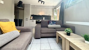A modern living room with a grey sofa, a wooden coffee table, and a small potted plant. - Boszicht 4 by Interhome (Oostkapelle)