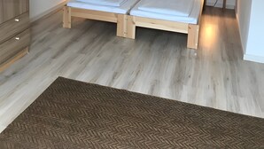 Une chambre à coucher avec un lit en bois, deux tables de chevet avec des lampes, une armoire et un tapis à motifs.