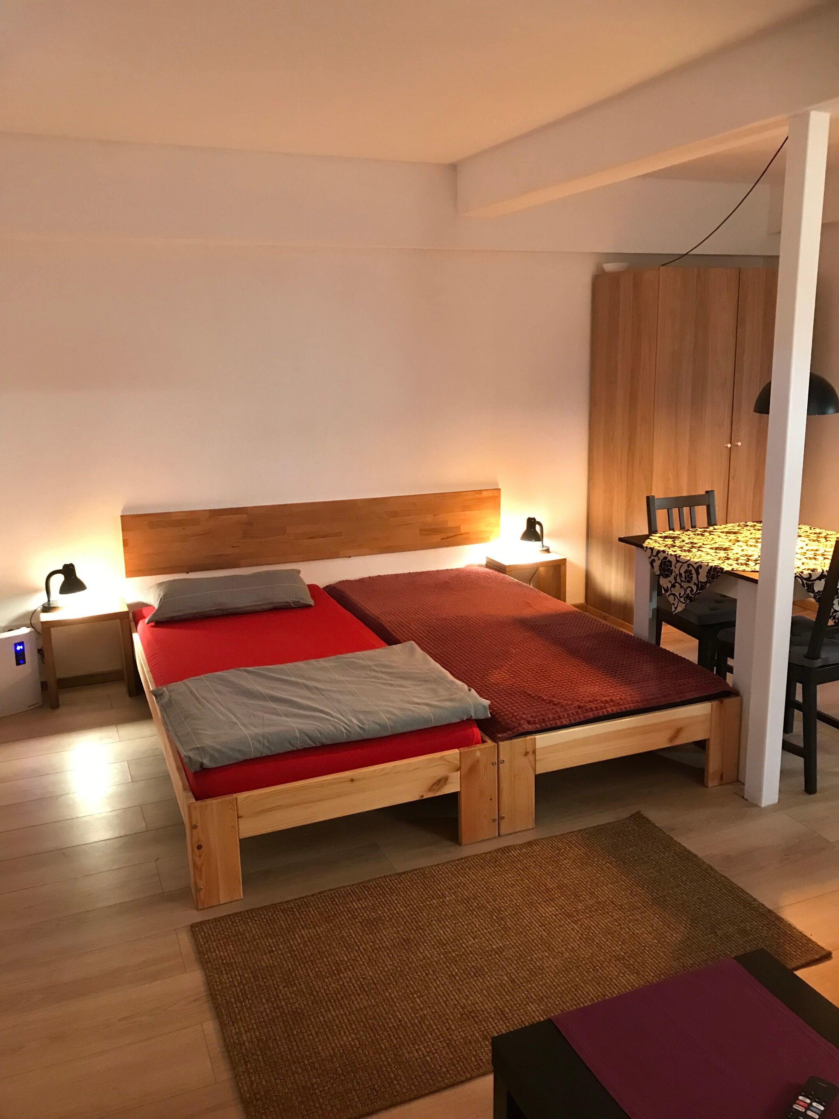 A bedroom with a wooden bed, bedside tables, a desk with a chair, and a wardrobe.