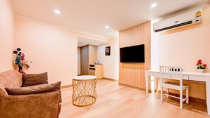 A modern living room with a sofa, a round table, a TV, and a white desk with a chair.
