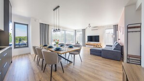 A modern living room with a dining area, a sofa, and a TV. - Apartamenty Sun & Snow Sand Dunes (Dziwnów)