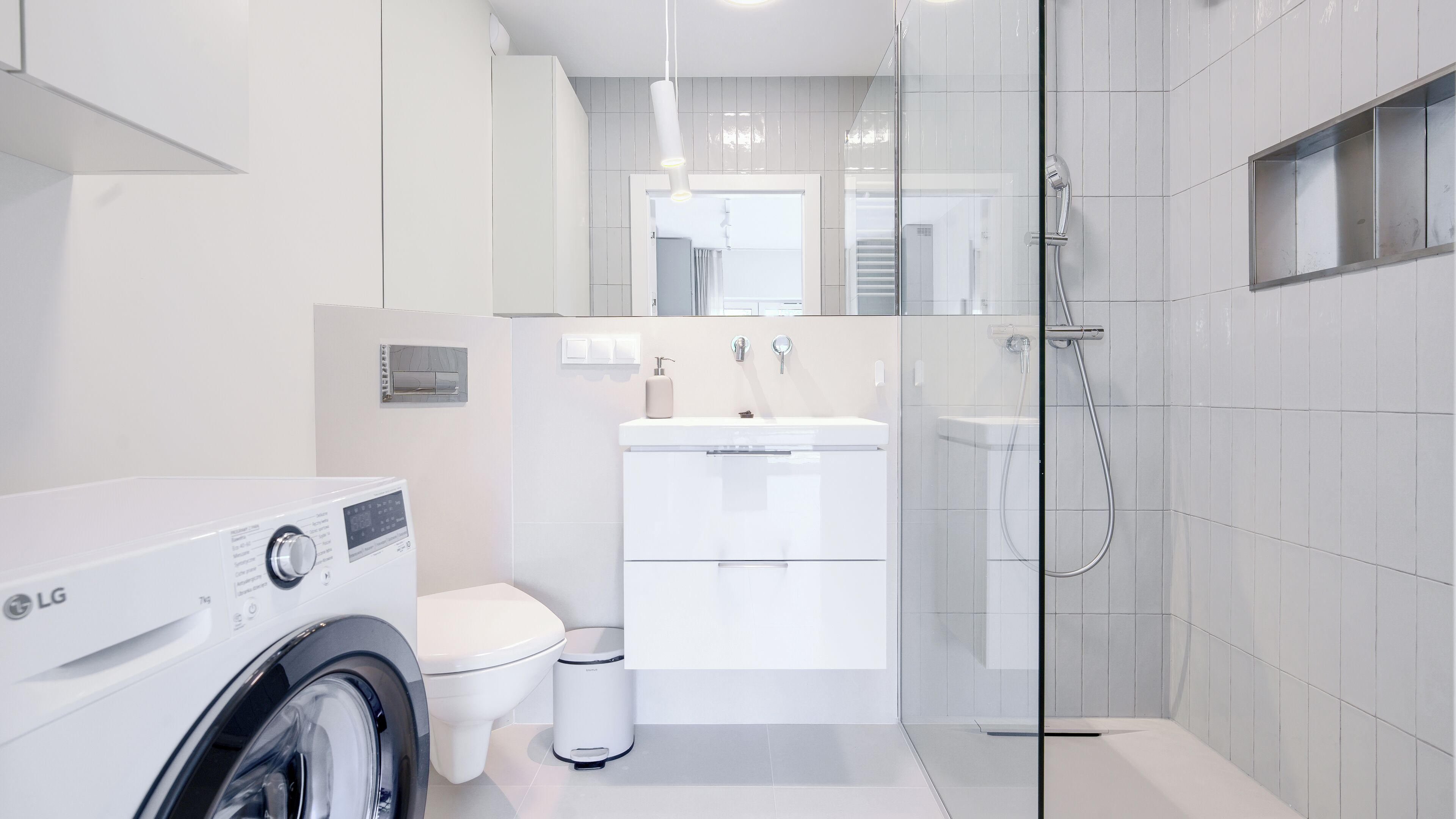 Ein modernes Badezimmer mit Waschmaschine, Toilette, Waschbecken und Duschkabine.