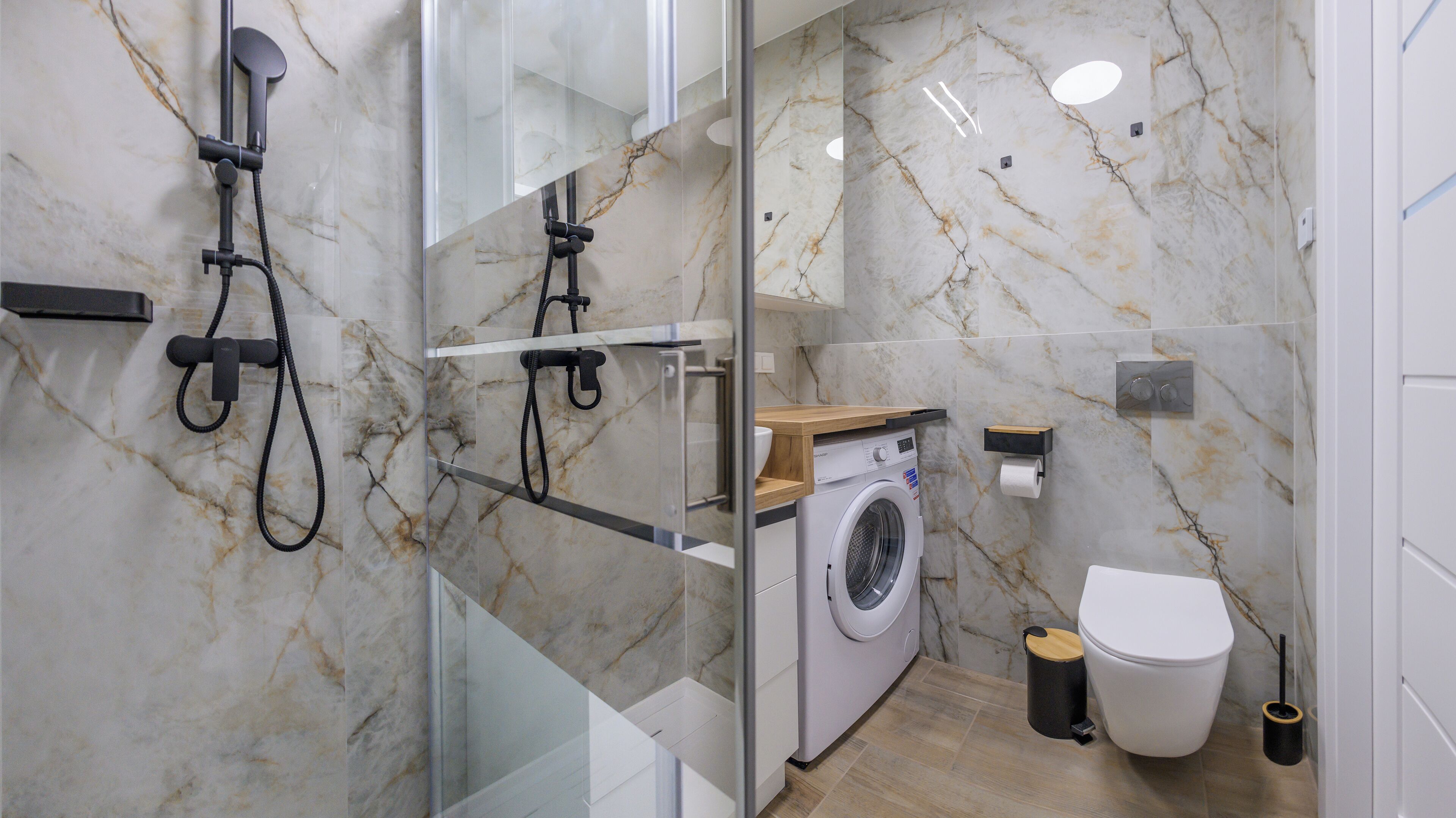 Un baño moderno con cabina de ducha de vidrio, lavadora e inodoro.