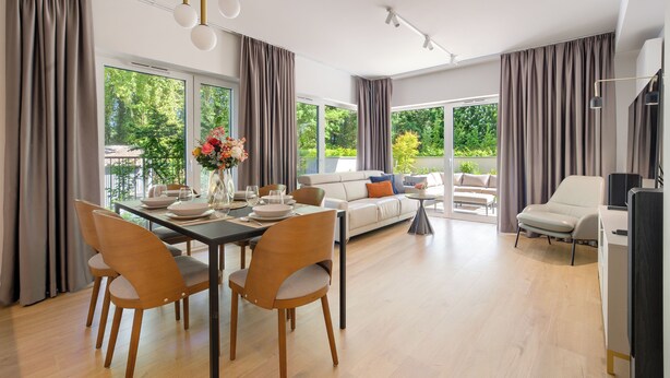 A modern living room with a dining area, large windows, and a balcony. - Apartamenty Sun & Snow Sand Dunes (Dziwnów)