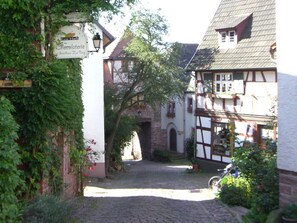 Eine schmale Kopfsteinpflasterstraße mit traditionellen Fachwerkhäusern, einem Schild für 'Eva H.B. Chocolaterie' und einem Fahrrad, das davor abgestellt ist.