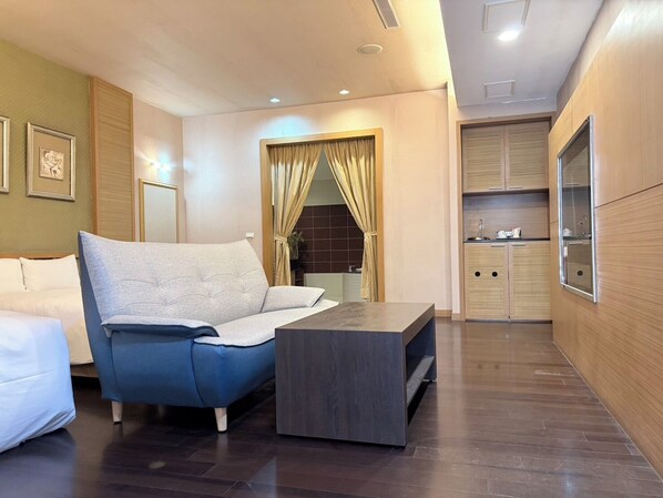 A modern hotel room with a sofa, a small table, and a kitchenette area. - Lisa motel (Kaohsiung)