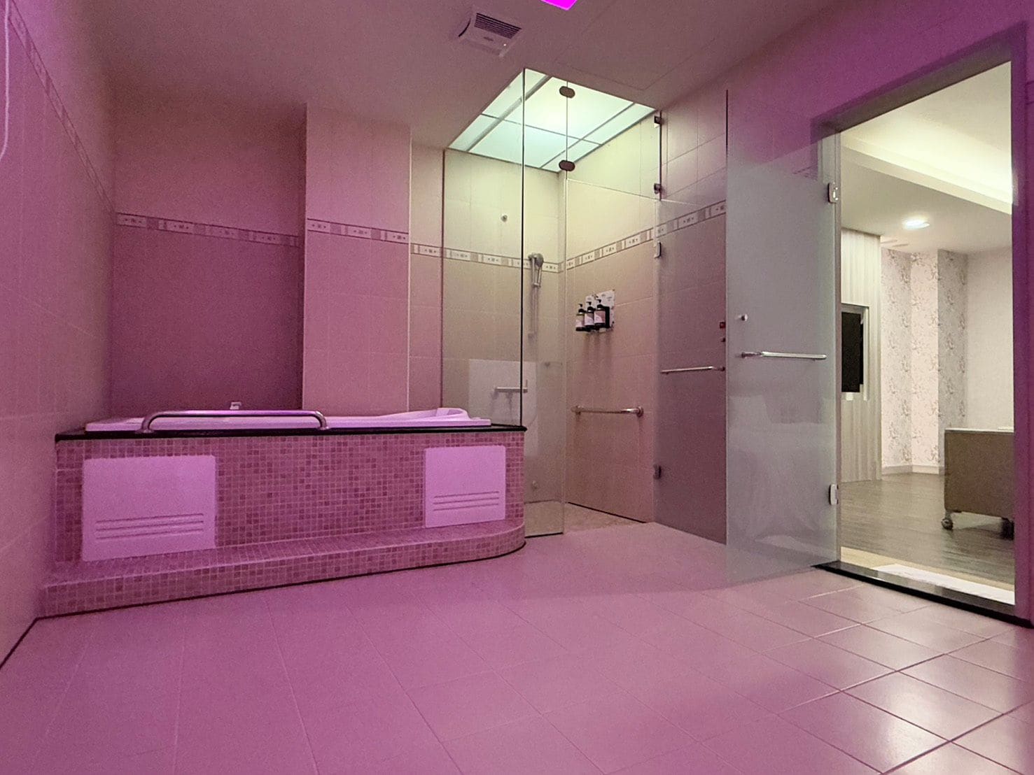 Un baño moderno con cabina de ducha de vidrio, lavamanos empotrado con perchero y espejo.