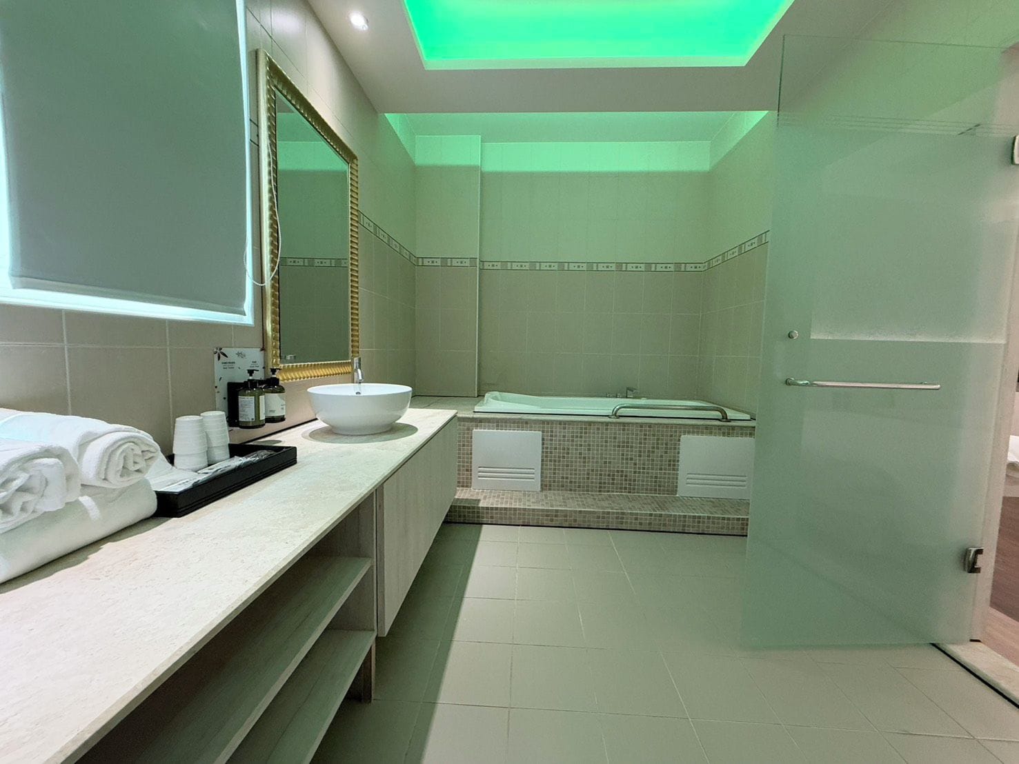 A modern bathroom with a large mirror, a white sink, and a bathtub.
