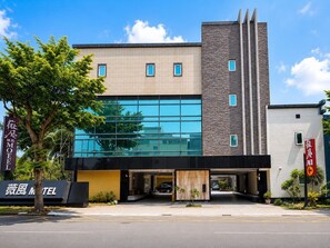 A modern building with a glass facade, a stone accent wall, and a sign for a motel. - Lisa motel (Kaohsiung)