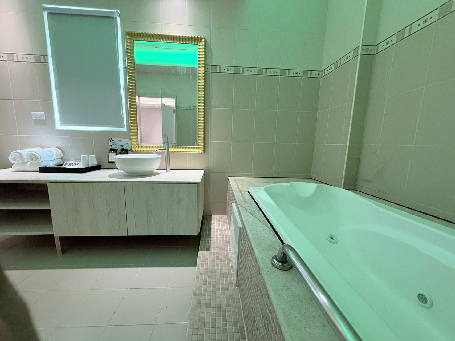 A modern bathroom with a freestanding bathtub, a vanity with a large mirror, and a towel rack.