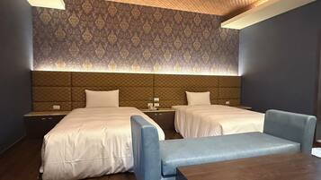 A hotel room with two beds, a small table, and a sofa.