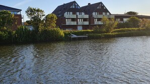 A riverside view with a row of houses, a dock, and a clear sky. - Holiday Apartment 'Watt'n Utsicht' with Sea View, Balcony and Wi-Fi (Nordstrand)