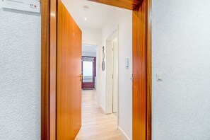 Un couloir avec des portes en bois, un interrupteur et un luminaire fixé au mur.