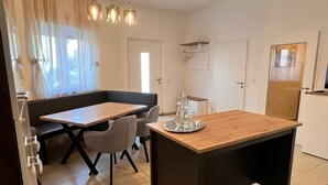 Une cuisine moderne avec un coin repas comprenant une table et des chaises en bois, un banc et des luminaires suspendus.