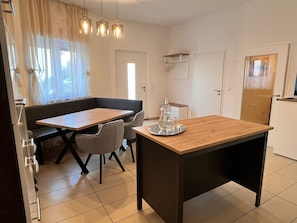 A modern kitchen with a dining area, including a wooden table and chairs, a bench, and pendant lighting.
