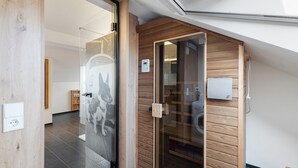 Un interior modern amb una porta de fusta, una paret de vidre amb una foto d'un gos i un termòstat visible.