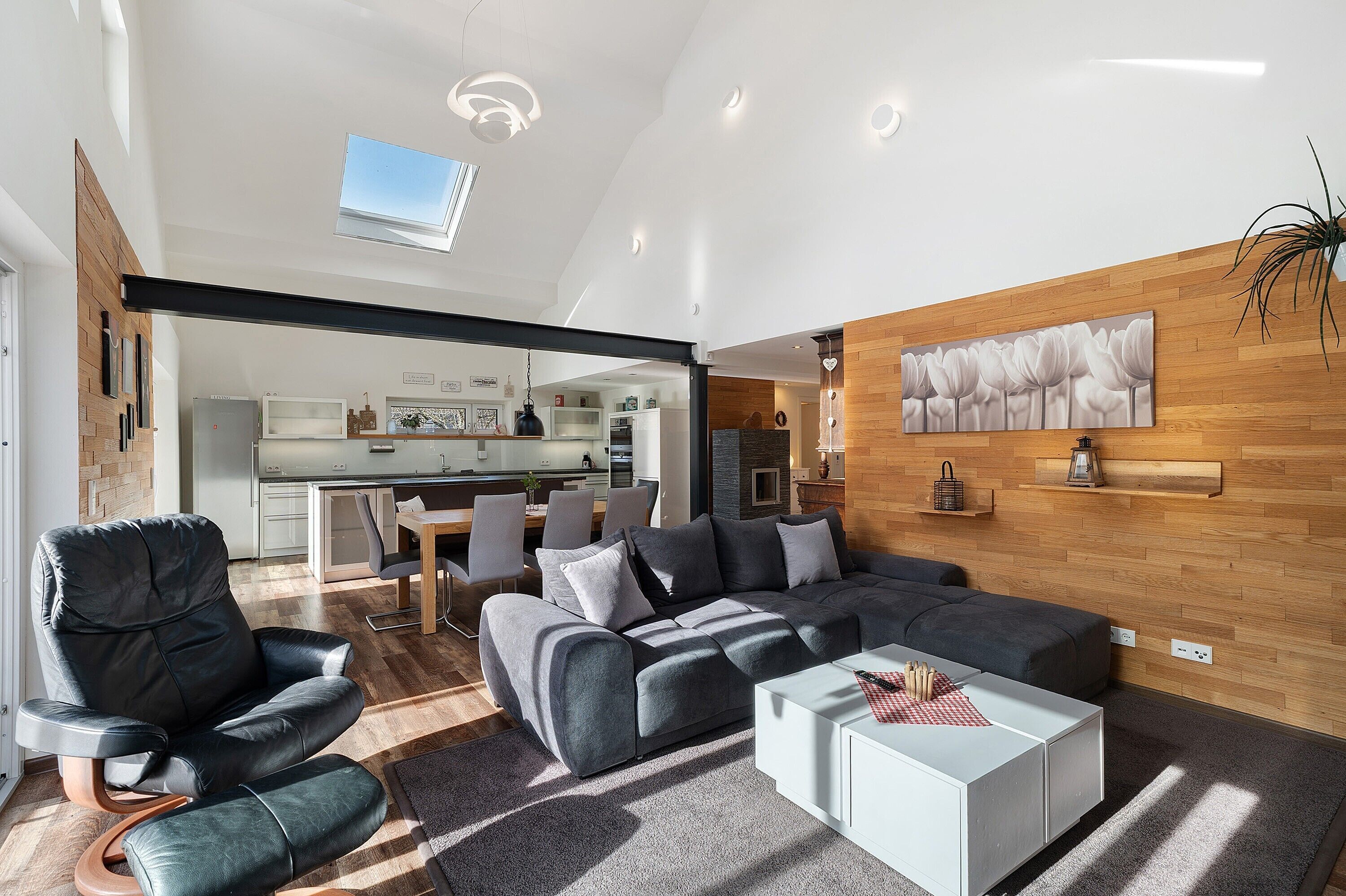 A modern living room with a sectional sofa, a black leather chair, and a white coffee table.