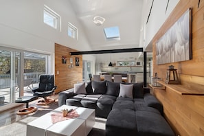 A modern living room with a sectional sofa, a black chair, and a white coffee table. - Holiday Apartment 'Forest' with Private Terrace and Wi-Fi (Renchen)