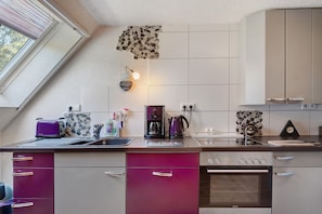 Eine moderne Küche mit Backofen, Kaffeemaschine und Wasserkocher.