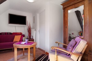 Ein Wohnzimmer mit einer Couch, einem Sessel, einem Holztisch und einem flachbildfernseher an der Wand.