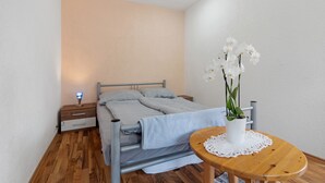 Una camera da letto con un letto, un comodino, un tavolino e un piccolo tavolo di legno con un vaso di fiori.
