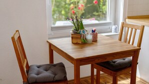 Un tavolo da pranzo in legno con sedie imbottite, una piccola pianta e una candela sopra il tavolo.