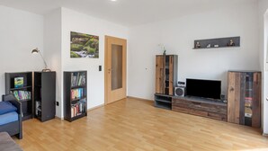 Ein modernes Wohnzimmer mit Holzboden, eingebauten Bücherregalen, einem Fernseher und einem Kamin.