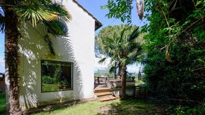 A white building with a large window, surrounded by lush greenery and a small patio area. - Awesome home in Montechiari with WiFi (Montechiari)
