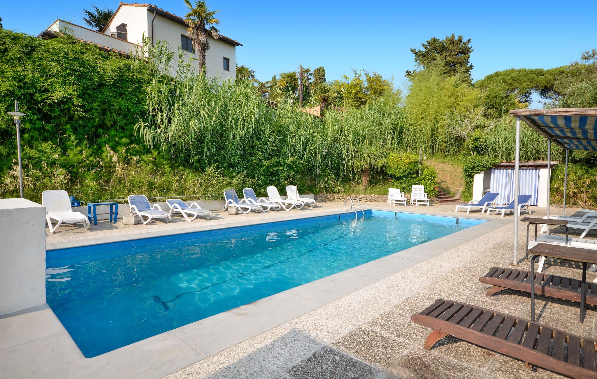 A swimming pool with lounge chairs and a small building in the background.