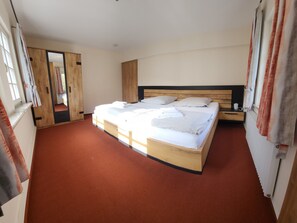 A bedroom with a large bed, wooden headboard, and a view of a bathroom. - Apartment 'Huhn' with Shared Terrace, Shared Garden and Wi-Fi (Schmallenberg)