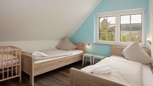 A bedroom with two wooden beds, a small table, and a window with a view. - Apartment 'Schwalbe' with Mountain View, Shared Terrace and Wi-Fi (Schmallenberg)