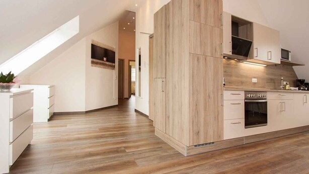A modern kitchen with wooden cabinets, a built-in oven, and a skylight. - Apartment 'Schwalbe' with Mountain View, Shared Terrace and Wi-Fi (Schmallenberg)