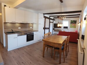 Una cocina moderna con armarios blancos, encimera de madera y comedor con mesa y sillas de madera.