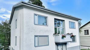 A two-story building with a white exterior, multiple windows, and a small balcony with potted plants. - Katariina Apartments (Kotka)